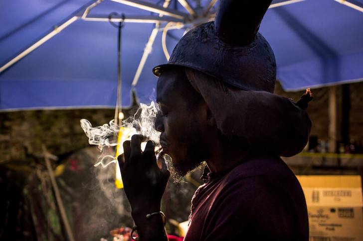 Duran Griffith, 31, wears his personal horned helmet in his backyard in Brownsville. Griffith is one of the leaders of Greenhouse Jab Jab, a Grenadian collective that encourages J'Ouvert attendees to dress in horns, paint, and oil as a means of reconnecting with their heritage.